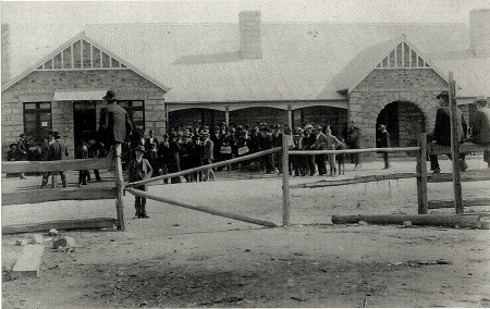 Capertee Railway Station Historical picture with people standing in the foreground behind a wooden fence.