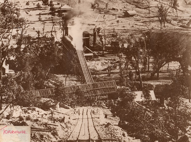 Historical picture of the Torbane Oil shale works, Capertee Valley NSW.It shows a picture of Rail line in the foreground, with the shale works retort in the middle and houses in the background all set in the bushland around that area.