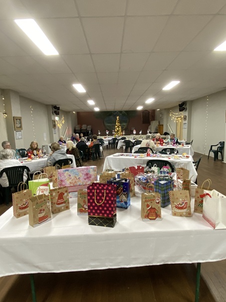 Capertee Christmas in July 2025 function in the Capertee Memorial Hall, Looking towards the stage. The table in foreground has the lucky door prizes, while the dinners are sitting between this table and the stage.